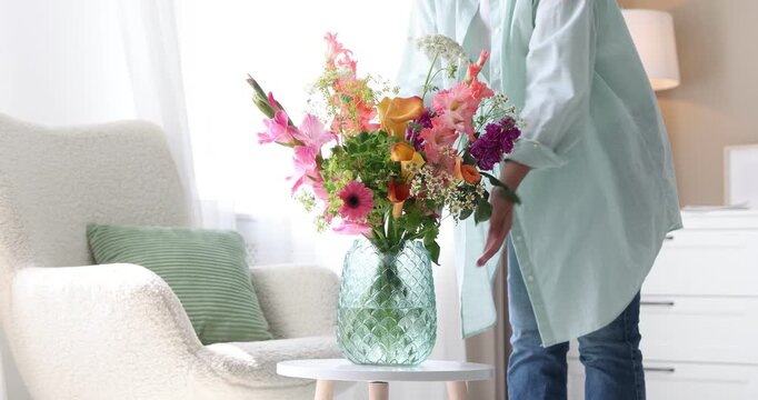 Woman arranging bouquet of beautiful summer flowers on table indoors, closeup