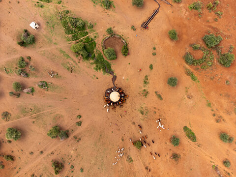 Aerial view of Amboseli National Park with livestock gathered around a circular watering hole in the arid landscape of Kajiado County, Kenya.