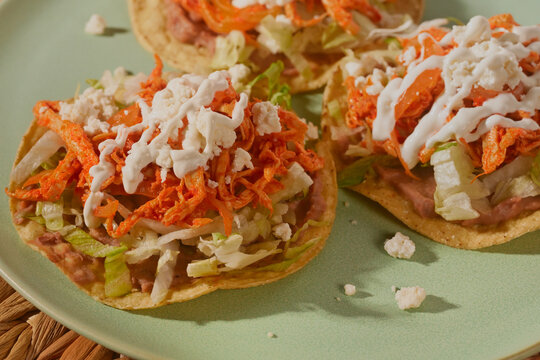 Mexican tostadas de tinga de pollo with fresh lettuce, sour cream, and cotija cheese. Direct flash