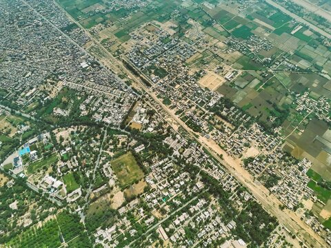 Aerial view of the urban landscape of Dera Ghazi Khan, featuring dense residential blocks, intersecting roads, and surrounding agricultural fields in Dera Ghazi Khan, Punjab, Pakistan.