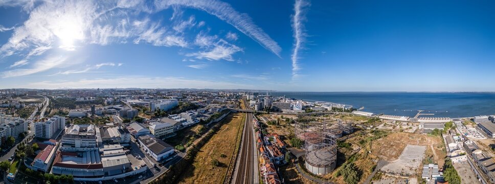 Aerial view of Parque das Nacoes featuring railway tracks, industrial structures, and the Tagus River under a clear blue sky, Lisbon, Lisbon, Portugal.