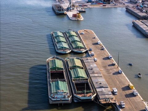 Aerial view of cargo barges moored at the Braco de Prata dock in the Tagus river with vehicles parked along the quay in Lisboa, Lisboa, Portugal.
