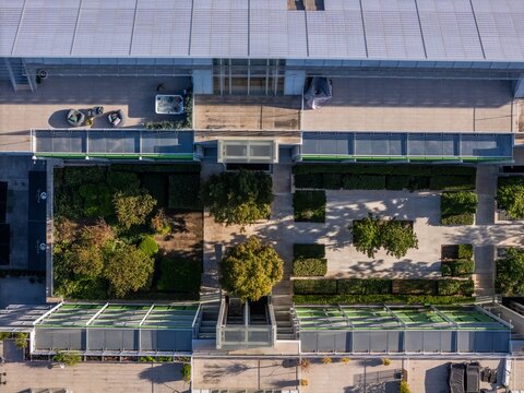 Aerial view of the Braco de Prata complex, featuring modern architecture with a central landscaped courtyard, trees, walkways, and rooftop terraces, Lisboa, Lisboa, Portugal.