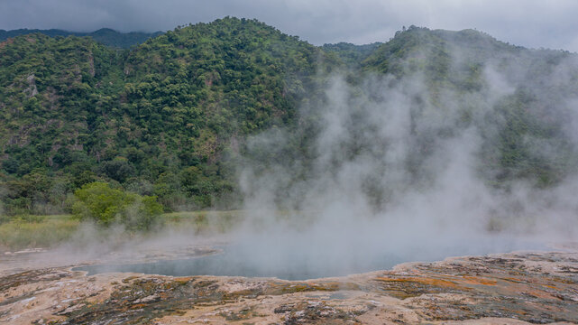 Aerial view of Sempaya Hot Springs with steam rising from the geothermal pool, surrounded by lush green mountains and dense forest in Fort Portal, Western Region, Uganda.