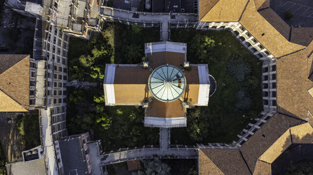 Aerial view of the historic sanatorium complex featuring a central dome, terracotta rooftops, and surrounding courtyards with lush greenery in Garbagnate Milanese, Lombardy, Italy.