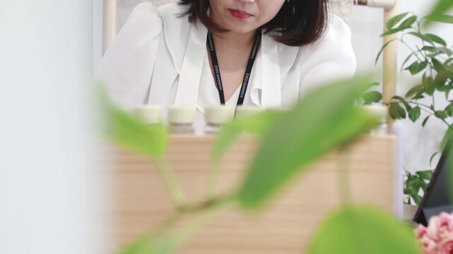 실내에서 식물과 나무 거치대 너머로 업무에 집중하고 있는 성인 여성의 모습