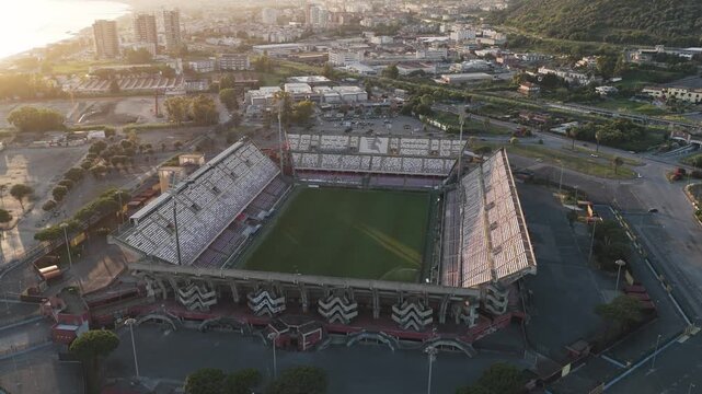 Salerno, Italy - 18 July 2026: Aerial view of Arechi Stadium with its distinctive seating tiers and green pitch under the warm light.