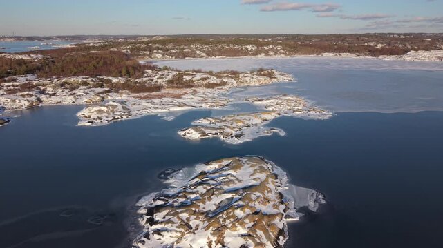 Aerial view of the snow-covered Stora Amundon island surrounded by frozen sea and rocky coastline in Hovas, Vastra Gotalands lan, Sweden.