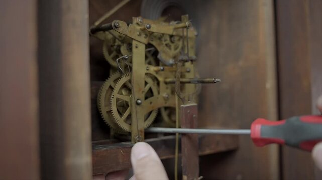 Extreme close up macro shot of a watchmaker using a precision screwdriver to delicately adjust the brass gears and internal mechanical parts of an antique clock.