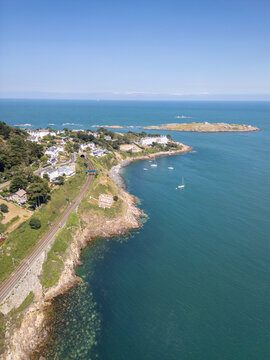 Aerial view of the Dalkey coastline featuring the railway line, residential houses, and Dalkey Island in the Irish Sea, Dublin, County Dublin, Ireland.