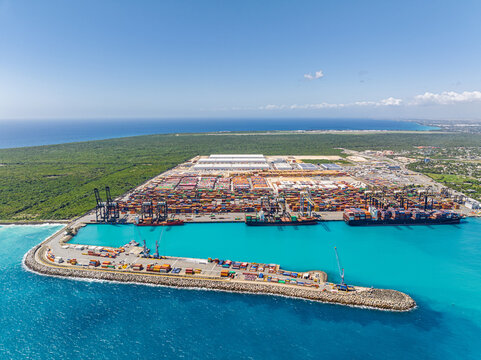 Aerial view of the DP World Dominicana container terminal with cargo ships, shipping containers, and cranes along the turquoise coastline in Boca Chica, Santo Domingo, Dominican Republic.