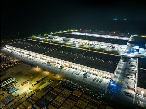 Aerial view of Caucedo Logistics Center at night with illuminated warehouse facilities, shipping containers, and loading docks in Andres, Santo Domingo, Dominican Republic.