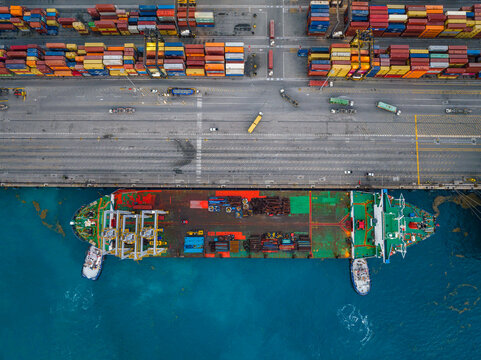 Aerial view of Caucedo Logistics Center featuring a cargo ship docked at the pier, colorful shipping containers, and trucks on the terminal in Andres, Santo Domingo, Dominican Republic.