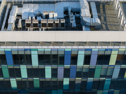 Aerial view of a modern data center building featuring a colorful glass facade and industrial HVAC cooling units on the rooftop in Krakow, Lesser Poland Voivode, Poland.