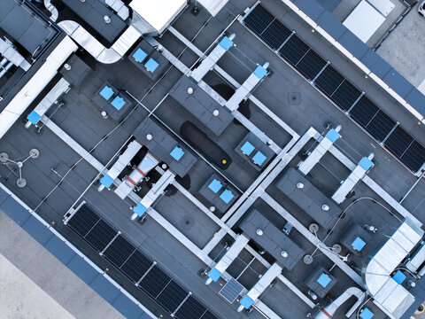 Aerial view of a modern industrial rooftop featuring extensive HVAC ventilation systems, cooling units, and integrated solar panel arrays in Krakow, Lesser Poland Voivode, Poland.