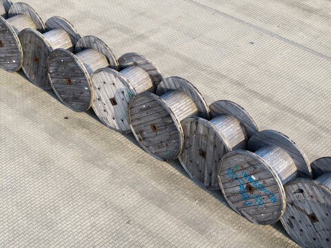 Krakow, Poland - 18 July 2026: Aerial view of Tele-Fonika Kable industrial site featuring a long row of large wooden cable reels arranged on a paved surface.