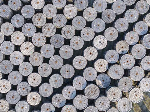 Krakow, Malopolskie, Poland - 18 July 2026: Aerial view of industrial cable reels stored at the Tele-Fonika Kable facility, showing rows of large wooden spools arranged in an outdoor yard.