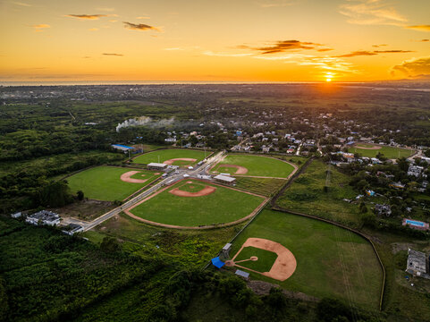 Aerial view of Quality Baseball Academy with multiple baseball fields surrounded by lush greenery at sunset in San Antonio de Guerra, Santo Domingo Provinc, Dominican Republic.