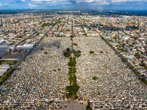 Aerial view of Maximo Gomez National Cemetery with its dense grid of tombs and central tree-lined path, surrounded by the urban landscape of Santo Domingo, Distrito Nacional, Dominican Republic.