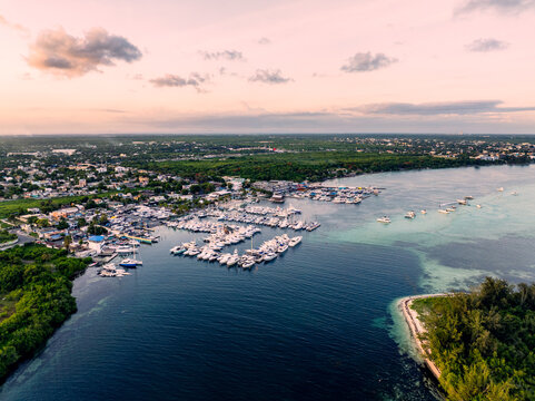 Aerial view of Club Nautico de Santo Domingo marina with yachts and boats, along the coast with lush vegetation and urban surroundings at sunset, Andres, Santo Domingo, Dominican Republic.