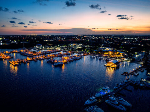 Aerial view of Club Nautico de Santo Domingo Inc. marina at dusk, with illuminated yachts and boats reflecting on calm water in Andres, Santo Domingo, Dominican Republic.