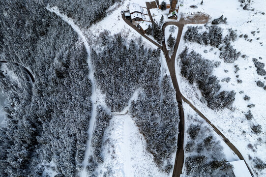 Aerial view of the snow-covered Mummelsee area with dense pine forests, winding roads, and scattered buildings in the winter landscape of Seebach, Baden-Wurttemberg, Germany.