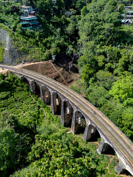 Aerial view of the historic Nine Arch Bridge surrounded by lush green tea plantations and dense forest in Demodara, Uva Province, Sri Lanka.