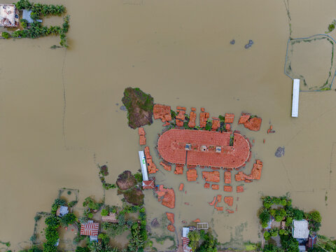 Aerial view of flooded landscape with submerged buildings and rooftops surrounded by murky floodwaters in Banshkhali Upazila, Chittagong Division, Bangladesh.