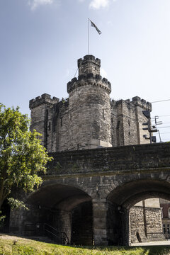 View of the historic Newcastle Castle Keep featuring stone battlements and arched masonry under a clear blue sky in Newcastle upon Tyne, England, United Kingdom.