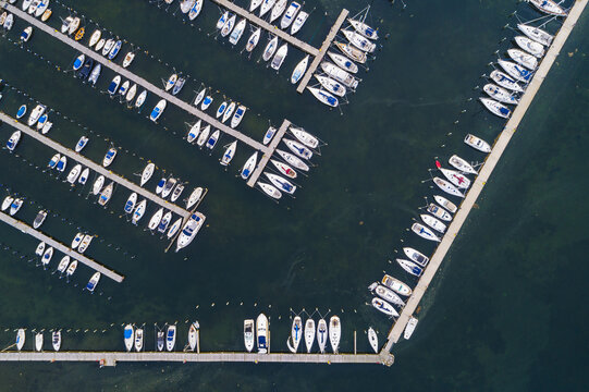 Aerial view of Sando marina featuring numerous sailboats and motorboats docked in organized rows within the calm waters of the harbor in Vallda, Hallands lan, Sweden.