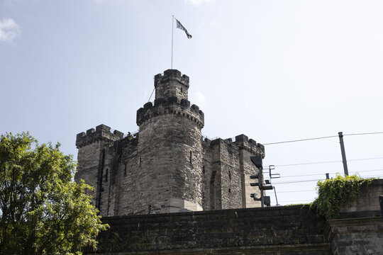 View of the historic stone keep of Newcastle Castle with battlements and a flag flying against a clear blue sky in Newcastle upon Tyne, England, United Kingdom.