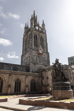 View of the historic Newcastle Cathedral with its prominent Gothic tower and clock face, set against a clear blue sky in Newcastle upon Tyne, England, United Kingdom.