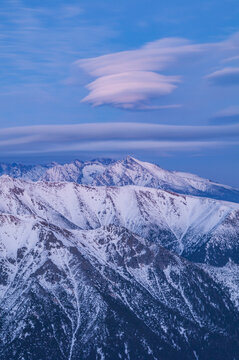 Aerial view of the snow-covered peaks of the High Tatras mountains under unique lenticular clouds in the sky in Vysoke Tatry, Presov Region, Slovakia.