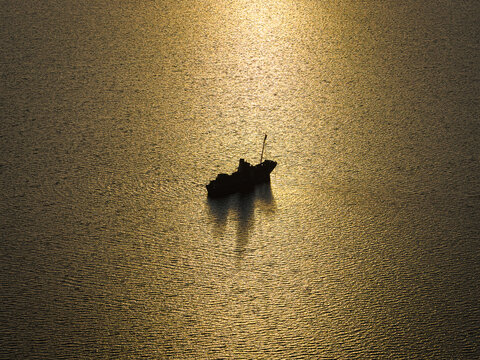 Aerial view of a ship silhouette floating on calm water during golden hour near Vancouver Peninsula, Western Australia, Australia.