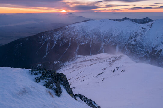 View of the snowy peak of Baranec in the Western Tatras during a sunset with strong winds blowing snow across the ridge in Jamnik, Zilina Region, Slovakia.