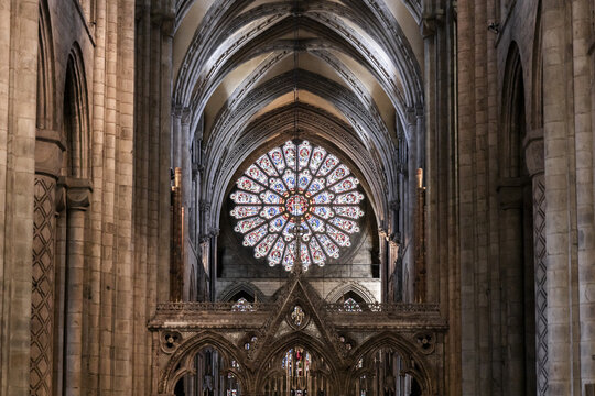 View of the interior of Durham Cathedral featuring the ornate rose window, soaring stone arches, and intricate gothic architecture in Durham, England, United Kingdom.