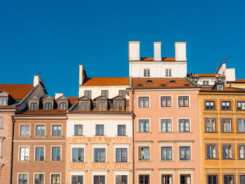 View of the colorful historic facades and ornate architectural details of the buildings in Warsaw Old Town under a clear blue sky in Warsaw, Masovian Voivodeship, Poland.