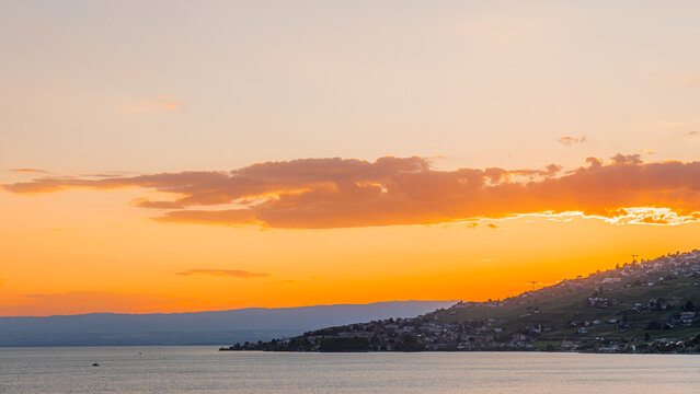 View of the picturesque vineyards and town of Bourg-en-Lavaux along the shores of Lake Geneva during a vibrant golden hour sunset, Bourg-en-Lavaux, Vaud, Switzerland.