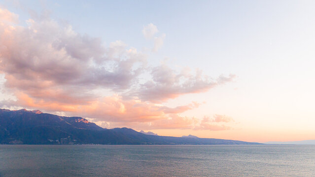 View of the sunset over Lake Geneva with mountains in the background in Bourg-en-Lavaux, Vaud, Switzerland.