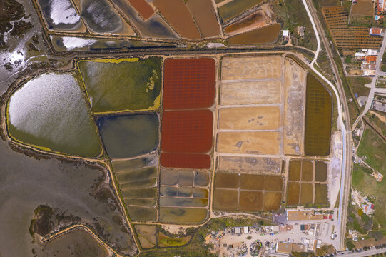Aerial view of Salinas do Grelha salt pans featuring vibrant red, green, and brown evaporation ponds arranged in geometric patterns Olhao, Faro, Portugal.