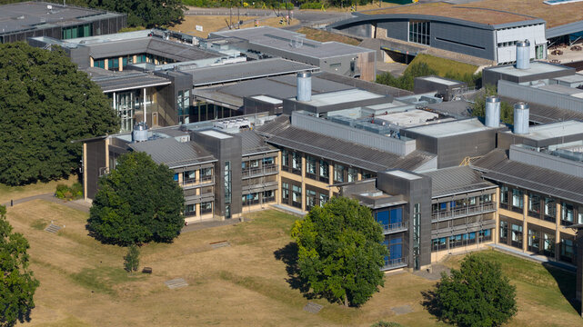 Aerial view of the Wellcome Genome Campus featuring modern research buildings, expansive green lawns, and mature trees in Hinxton, England, United Kingdom.