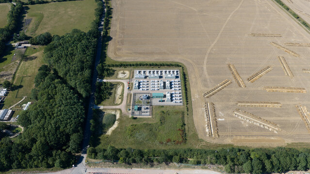 Aerial view of Pelham Storage Limited facility with rows of battery storage units and electrical infrastructure surrounded by fields and woodland in Bishop's Stortford, England, United Kingdom.