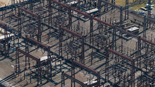 Aerial view of Pelham Storage Limited electrical substation featuring complex metal structures, high-voltage equipment, and power lines in Bishop's Stortford, England, United Kingdom.