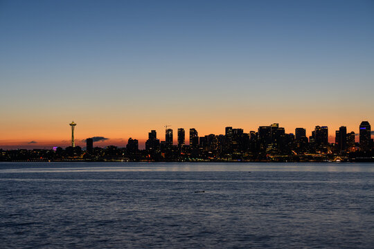 View of the Seattle skyline at sunset with the Space Needle silhouette against the colorful evening sky across the water in Seattle, Washington, United States.