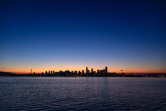 View of the Seattle skyline at twilight from Don Armeni Boat Ramp, featuring the Space Needle and skyscrapers silhouetted against a sunset sky, Seattle, Washington, United States.