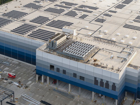 Skawina, Poland - 19 July 2026: Aerial view of the Lidl distribution centre under construction, showing a large roof with solar panels, cooling units, and construction equipment.