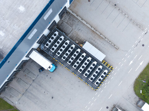 Aerial view of a logistics hub featuring a warehouse building with loading docks, a parked truck, and a row of industrial HVAC units on the roof in Skawina, Lesser Poland Voivode, Poland.