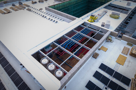 Aerial view of the ai data center cooling system featuring complex red and blue piping, industrial fans, and solar panels installed on a flat rooftop in Krakow, Lesser Poland Voivode, Poland.
