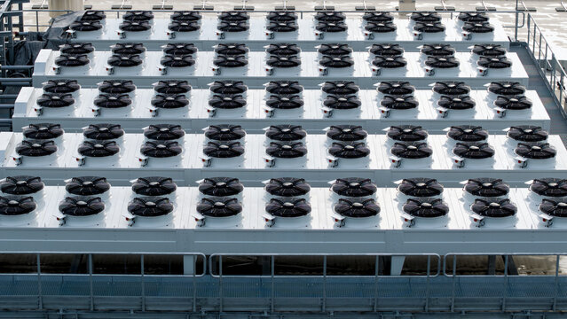 Aerial view of an industrial data center cooling system featuring rows of large fans on a rooftop in Krakow, Lesser Poland Voivode, Poland.