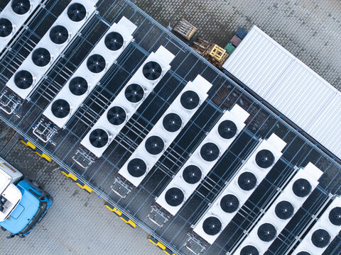 Aerial view of an industrial cooling system for a data center with rows of large fans on a rooftop, next to a blue truck in Krakow, Lesser Poland Voivode, Poland.